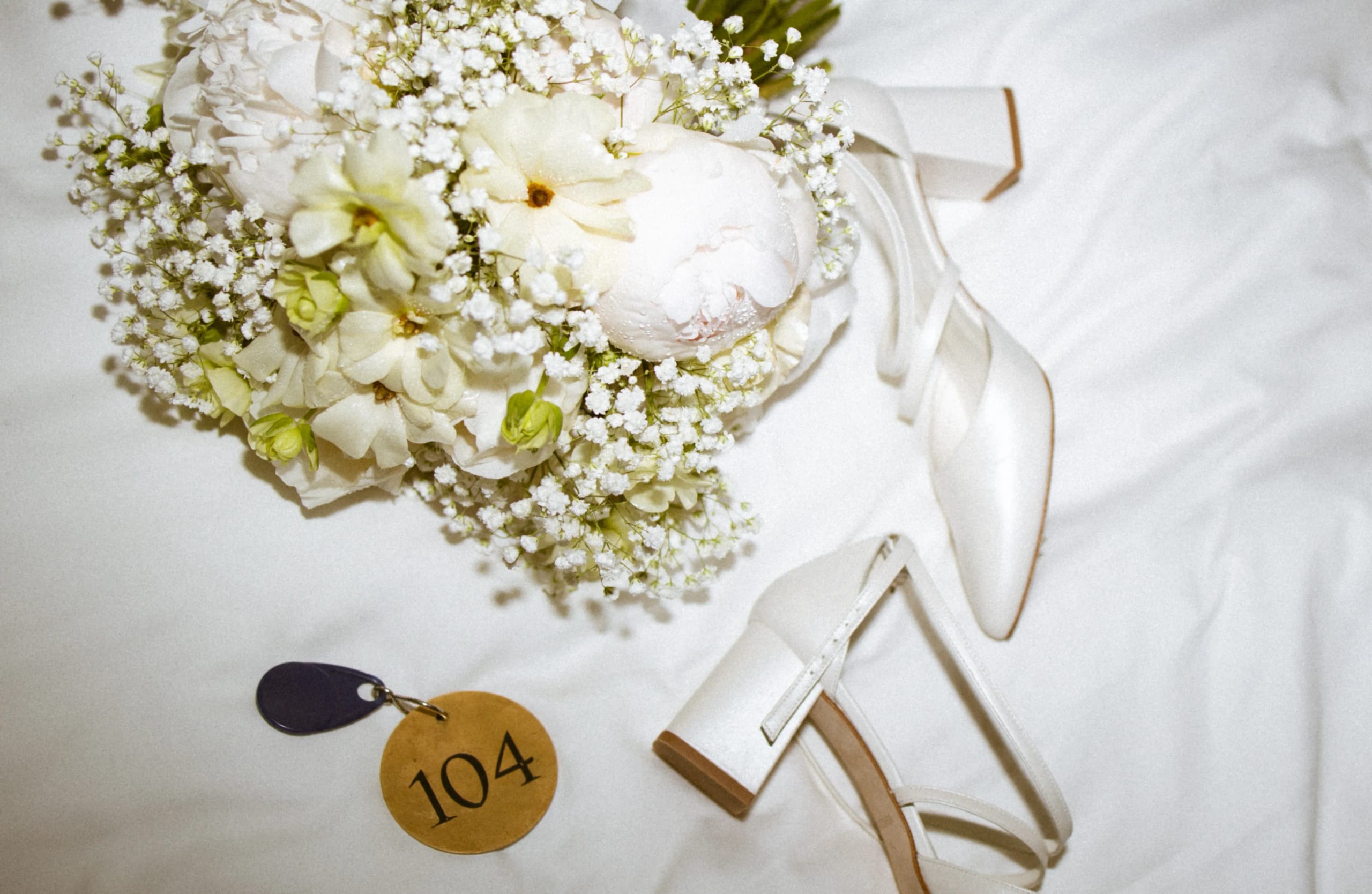 Detailfoto van een wit bruidsboeket met gipskruid en elegante witte bruidsschoenen
